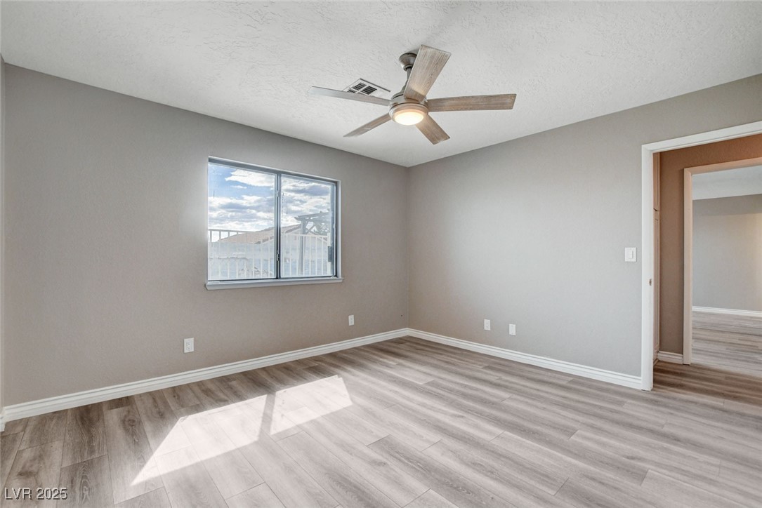 1118 Olmo Way Boulder City, NV 89005 - Photo 17 of 45 Unfurnished bedroom with a textured ceiling, light wood-style floors, and a ceiling fan