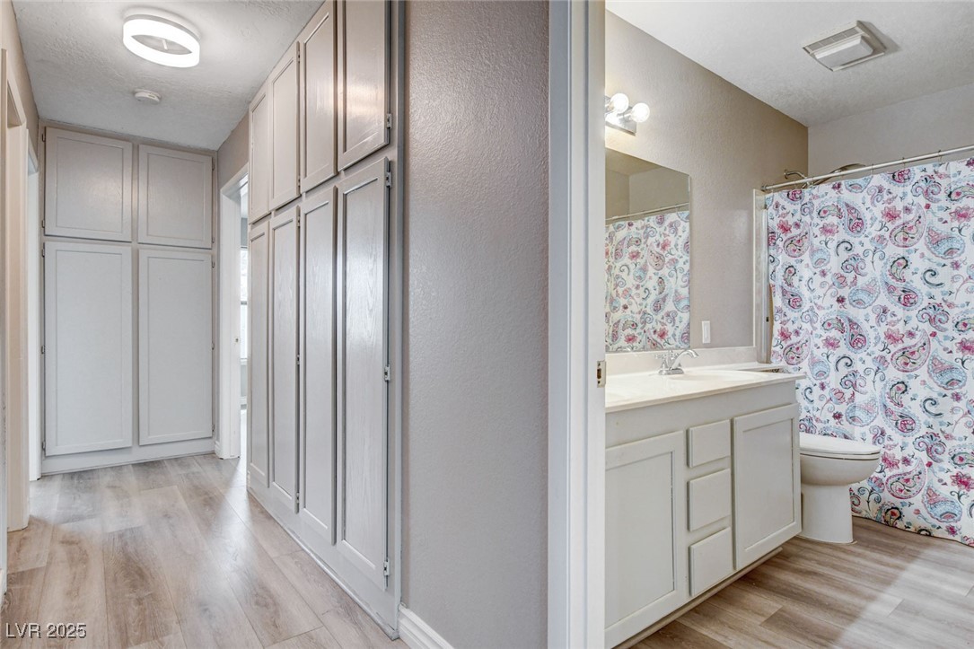 1118 Olmo Way Boulder City, NV 89005 - Photo 20 of 45 Full bathroom featuring light wood-style flooring, vanity, a textured ceiling, and a shower with curtain