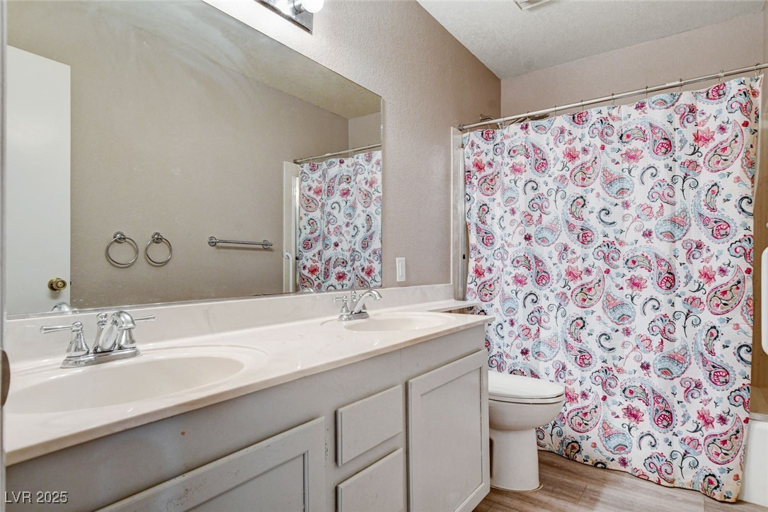 1118 Olmo Way Boulder City, NV 89005 - Photo 21 of 45 Full bathroom with double vanity, light wood-type flooring, shower / bath combo with shower curtain, and a textured wall