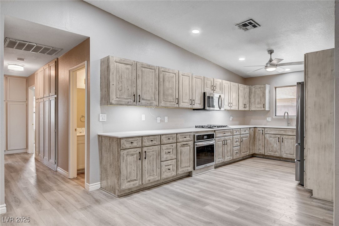 1118 Olmo Way Boulder City, NV 89005 - Photo 8 of 45 Kitchen with light countertops, lofted ceiling, light wood-style flooring, light brown cabinets, and appliances with stainless steel finishes