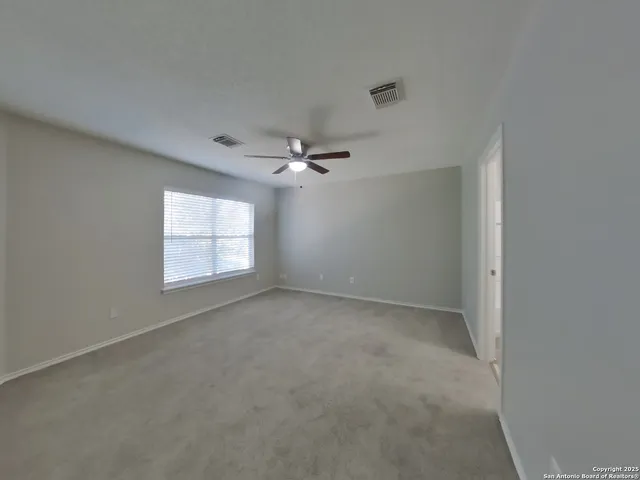 an empty room with windows and ceiling fan view