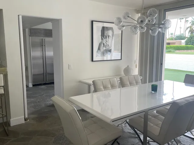 a view of a dining room with furniture a chandelier and large windows