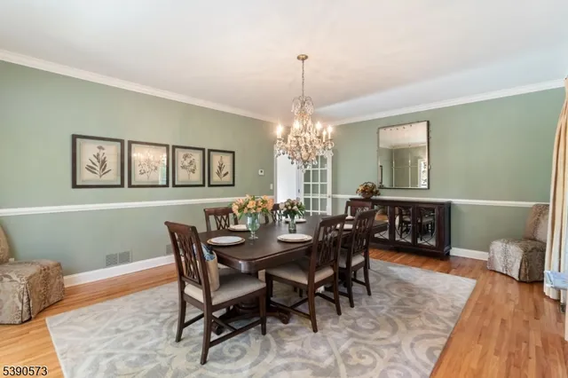 a view of a dining room and livingroom with furniture wooden floor a rug a potted plant and a chandelier