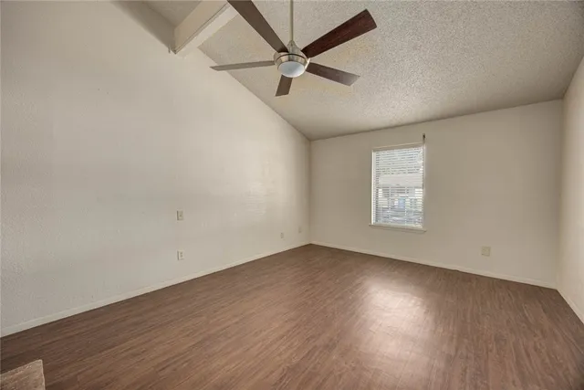 an empty room with wooden floor ceiling fan and windows