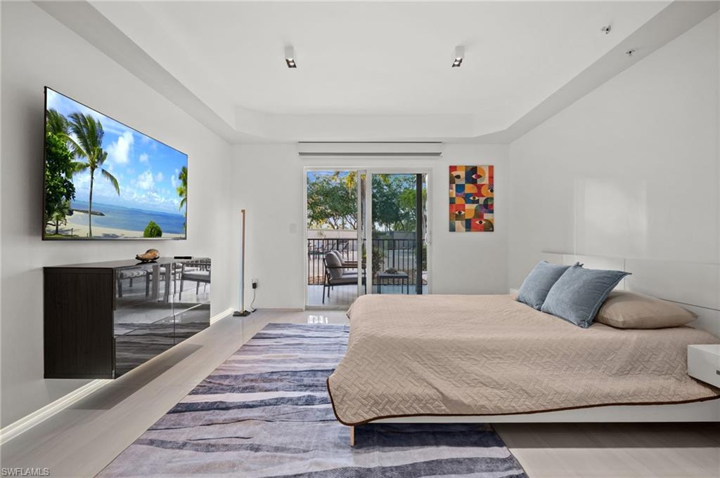 1100 Pine Ridge Road, Unit B103 Naples, FL 34108 - Photo 21 of 38 a bedroom with a large bed and a flat screen tv
