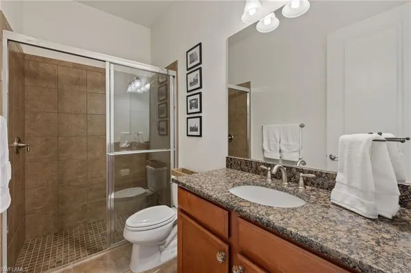 a bathroom with a granite countertop sink toilet and shower