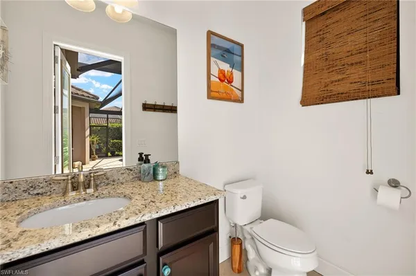 a bathroom with a granite countertop toilet sink and mirror