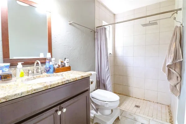a bathroom with a granite countertop sink a toilet and shower