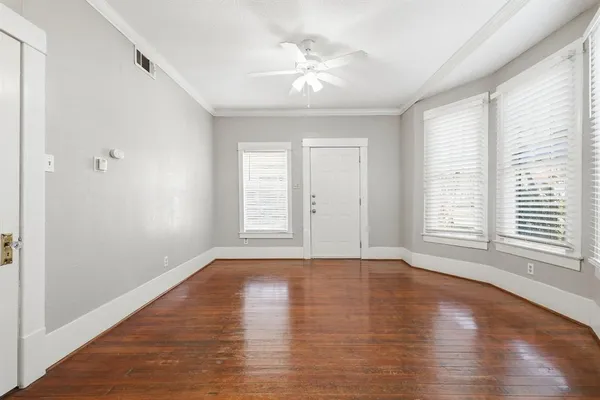 a view of an empty room with wooden floor and a window