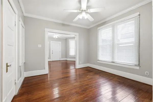 a view of an empty room with wooden floor and a window