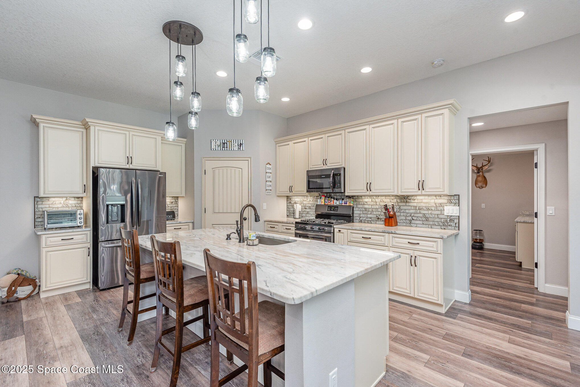 3620 Maebert Road Mims, FL 32754 - Photo 11 of 35 a kitchen with stainless steel appliances a dining table chairs refrigerator and cabinets