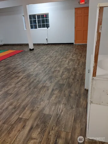 a view of an empty room with wooden floor and a window