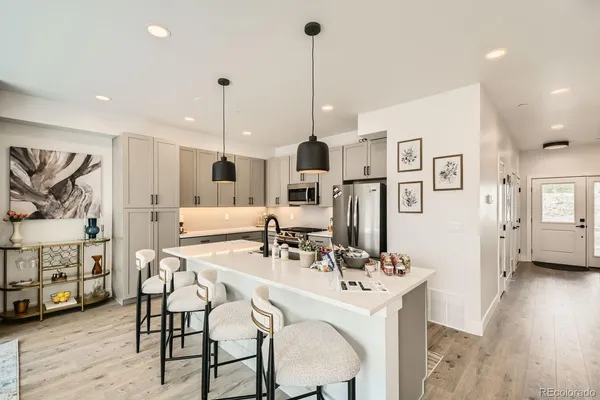 a kitchen with stainless steel appliances kitchen island granite countertop a table chairs and a refrigerator