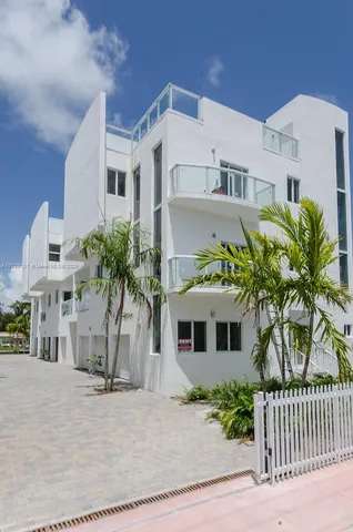 a view of a white building with a yard and table and chairs