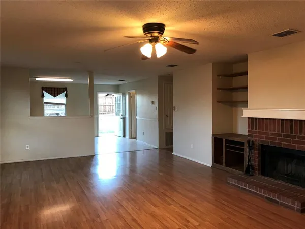 a view of a livingroom with wooden floor a ceiling fan and windows