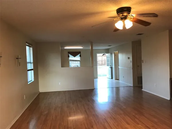 a view of an empty room with window and wooden floor