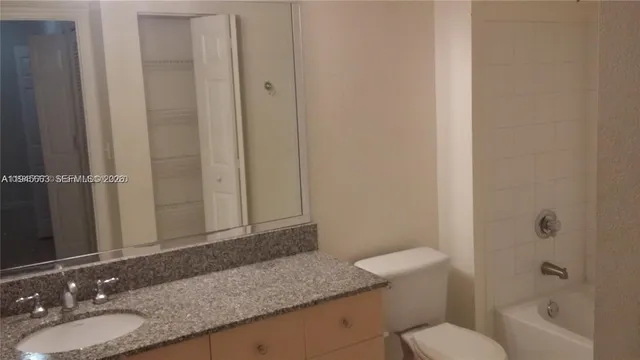 a bathroom with a granite countertop sink a toilet and shower