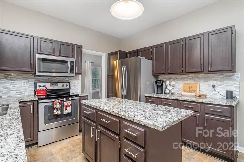 7201 Reedy Creek Road Charlotte, NC 28215 - Photo 10 of 30 a kitchen with kitchen island granite countertop a stove microwave and refrigerator