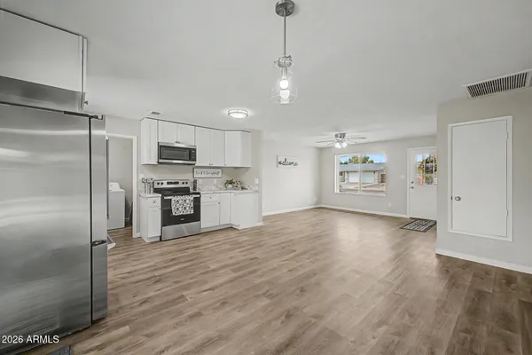 a kitchen with stainless steel appliances a stove top oven a sink a refrigerator and white cabinets
