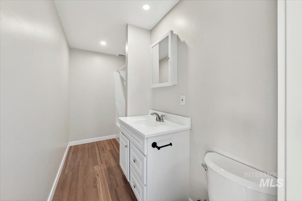 109 Parma Road Parma, ID 83660 - Photo 17 of 31 Bathroom featuring luxury plank flooring, a white vanity with integrated sink, and a wall-mounted medicine cabinet