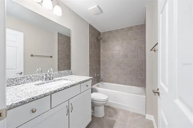a bathroom with a granite countertop sink a toilet and bathtub