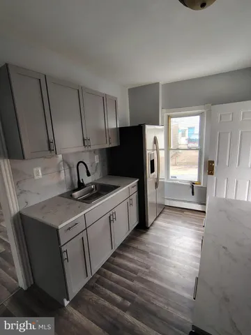 a kitchen with stainless steel appliances a sink cabinets and a wooden floor
