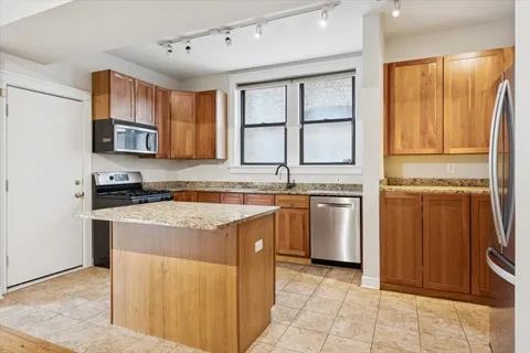 a kitchen with stainless steel appliances granite countertop a stove a sink and a refrigerator