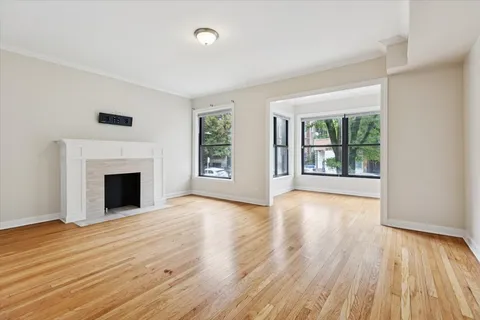 an empty room with wooden floor fireplace and windows