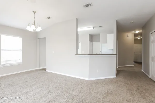 an empty room with chandelier fan and windows