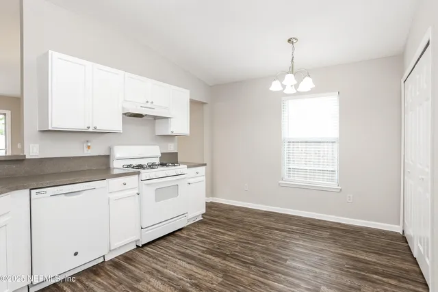 a kitchen with granite countertop white cabinets and white appliances