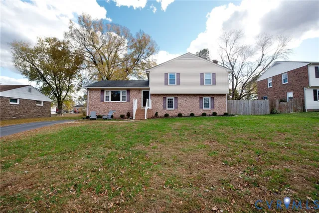 a view of a yard in front of a house with plants and large tree