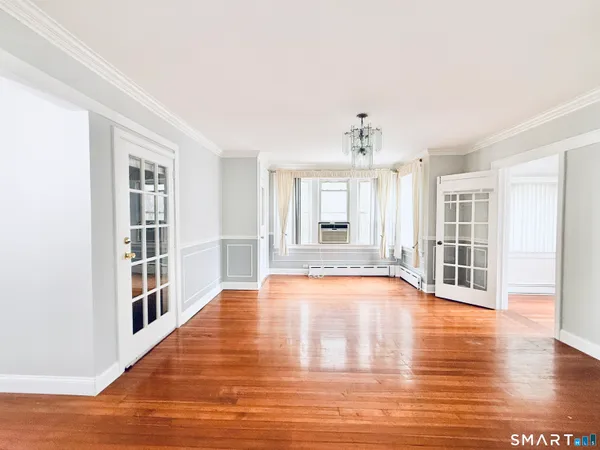a view of an empty room with window and wooden floor