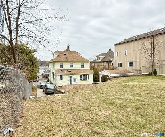 a front view of a house with a yard covered with snow and cars