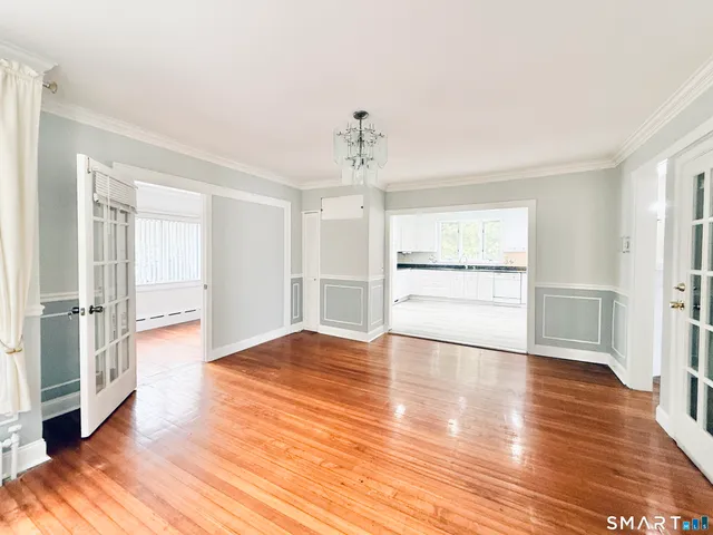 a view of empty room with wooden floor and kitchen view