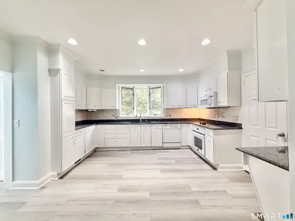 a kitchen with granite countertop white cabinets and white appliances