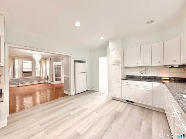 a large kitchen with granite countertop a large counter top and stainless steel appliances