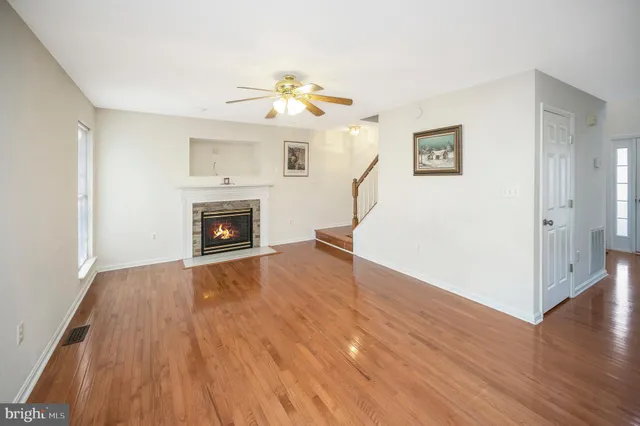 an empty room with wooden floor fireplace and windows