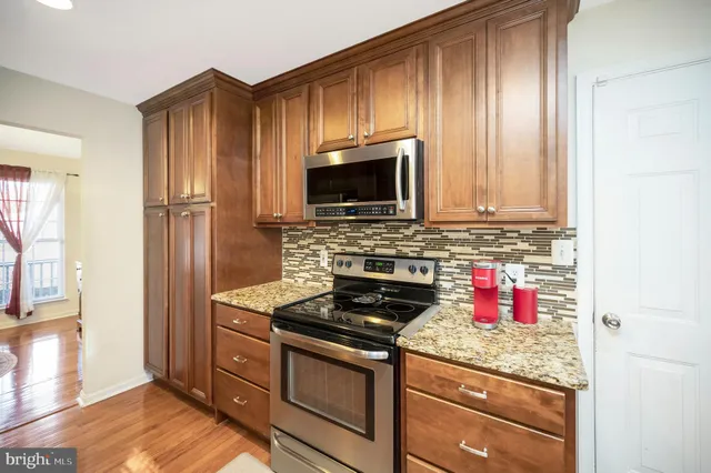 a kitchen with granite countertop wooden cabinets and stainless steel appliances