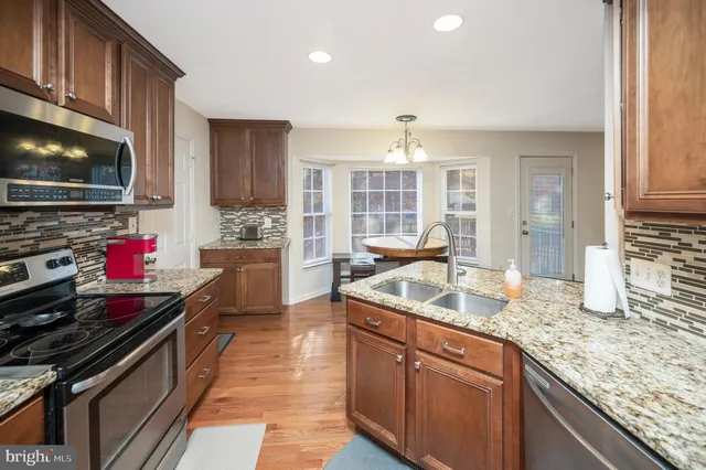 a kitchen with stainless steel appliances granite countertop a sink stove and cabinets