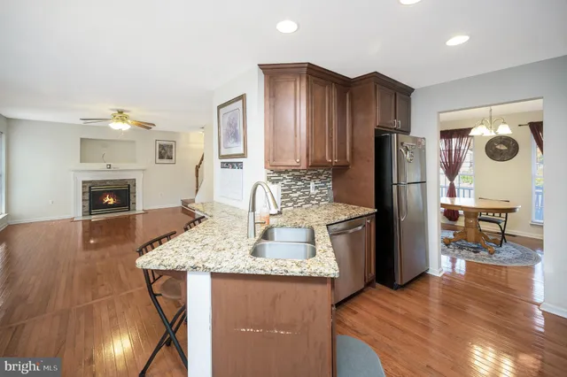 a kitchen with refrigerator a stove a sink and a dining table with wooden floor