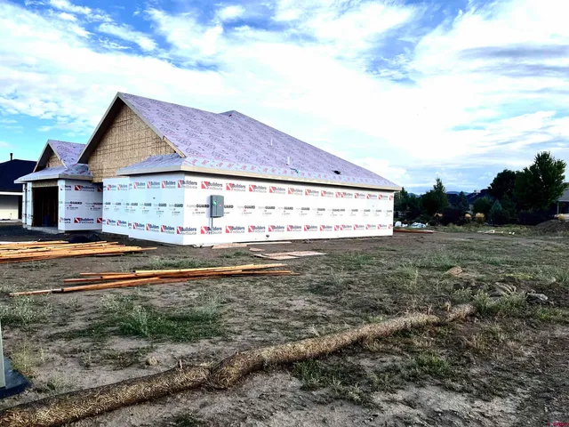a view of a white house next to a yard with big trees