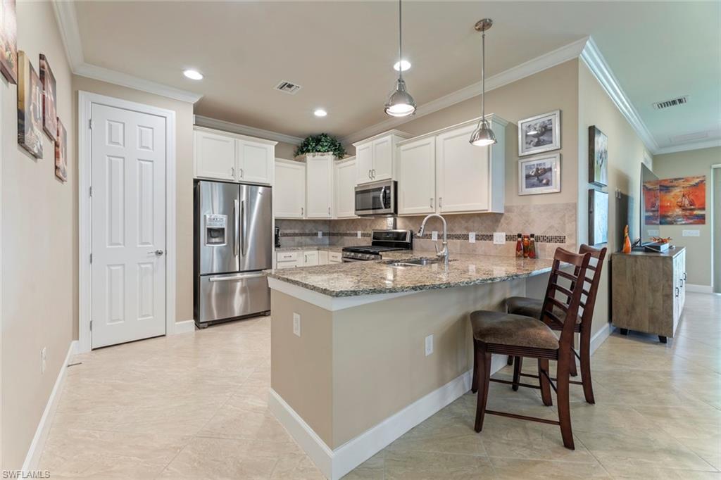 20191 Torch Key Way Estero, FL 33928 - Photo 11 of 39 a kitchen with stainless steel appliances granite countertop a refrigerator a stove a sink a dining table and chairs with wooden floor