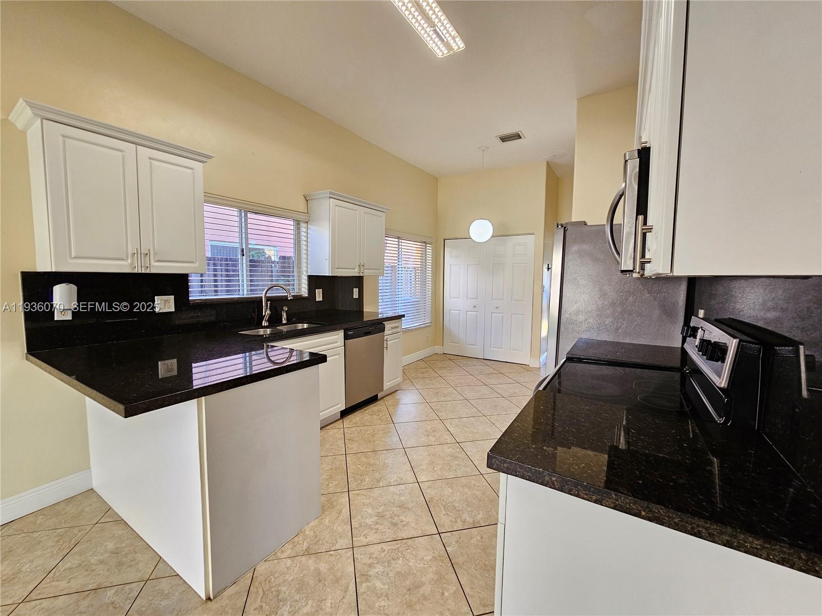 14209 Southwest 160th Court Miami, FL 33196 - Photo 7 of 24 a kitchen with granite countertop a stove and a refrigerator