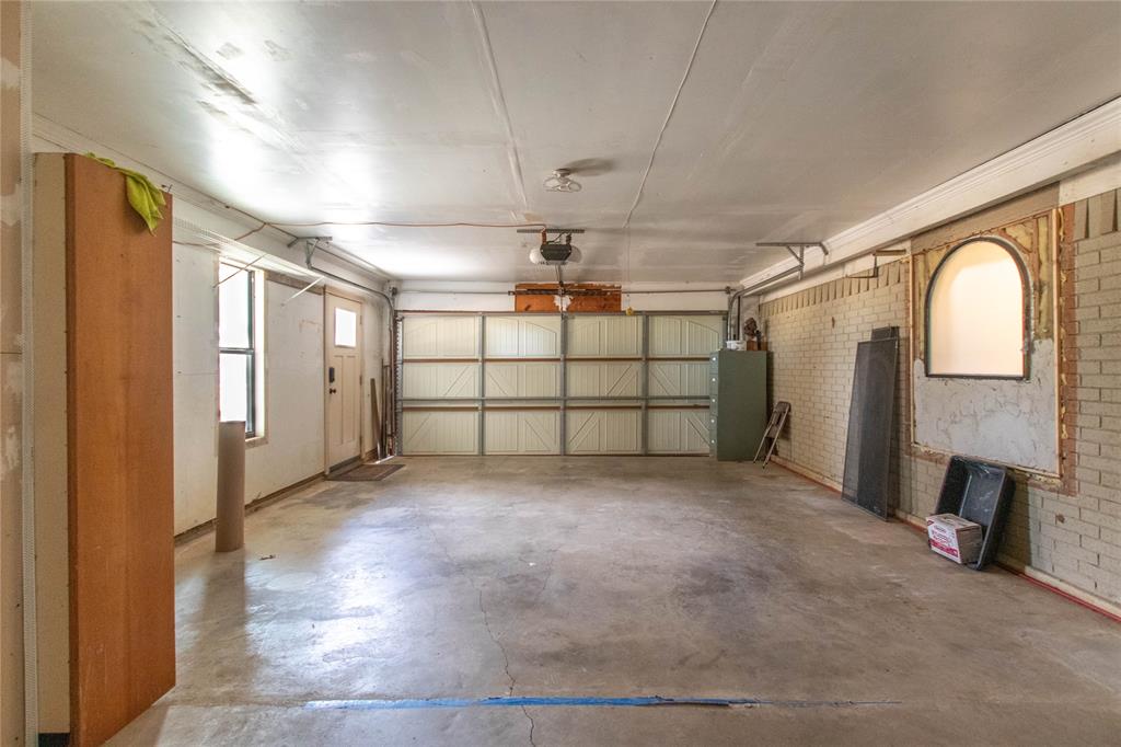 308 Sanders Road Denton, TX 76210 - Photo 25 of 31 Concrete flooring, automatic garage door, recessed lighting, and a brick wall