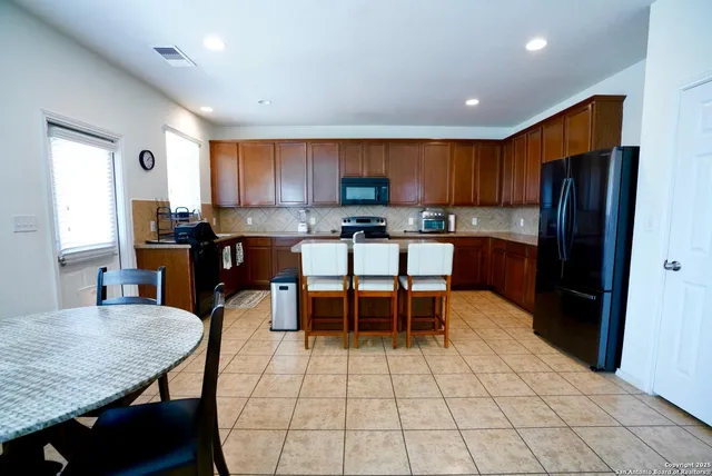 a kitchen with a dining table chairs and refrigerator