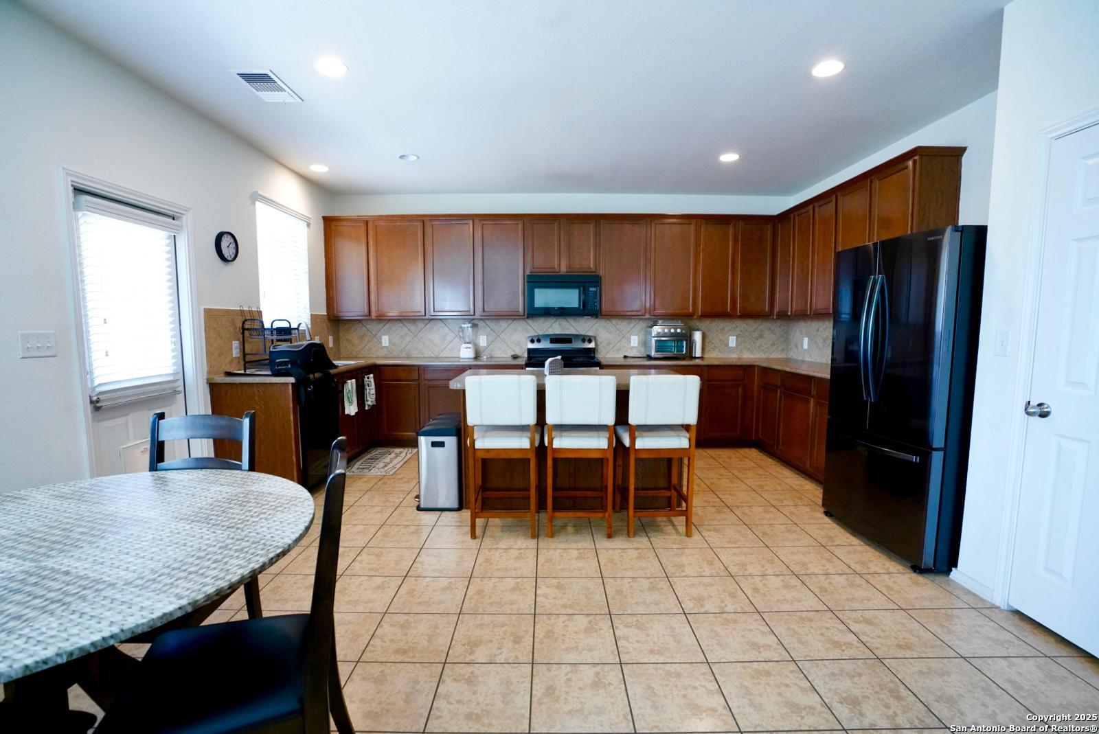3906 Bent Grass San Antonio, TX 78261 - Photo 7 of 23 a kitchen with a dining table chairs and refrigerator