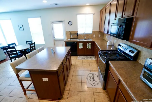 a kitchen with stainless steel appliances granite countertop a stove a refrigerator a sink a dining table and chairs with wooden floor