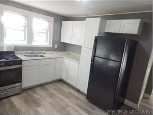 a kitchen with a sink a refrigerator a window and cabinets