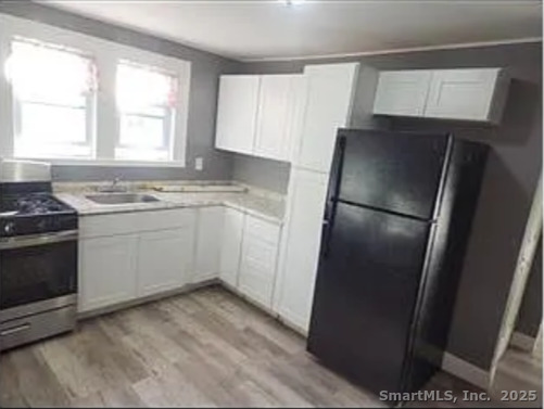 326 Wilmot Avenue Bridgeport, CT 06607 - Photo 2 of 4 a kitchen with a sink a refrigerator a window and cabinets