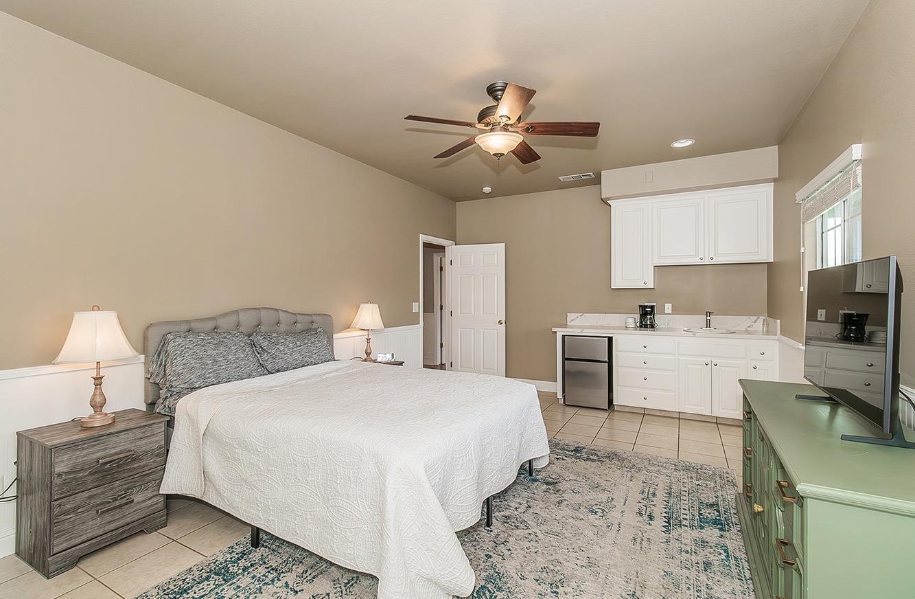 21777 Tollhouse Road Clovis, CA 93619 - Photo 27 of 99 a bedroom with a bed a chandelier and flat screen tv